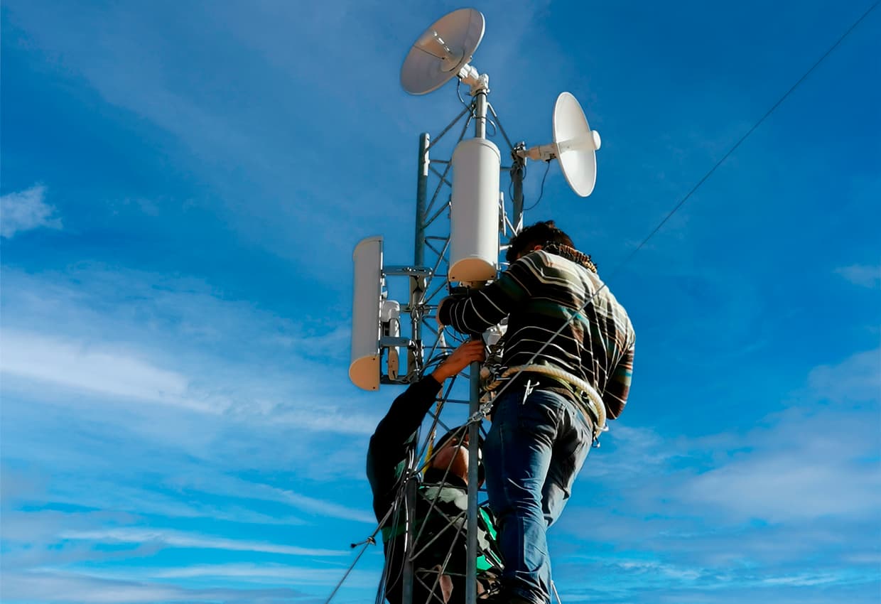Técnicos instalando antena de radioenlace para telecomunicaciones.